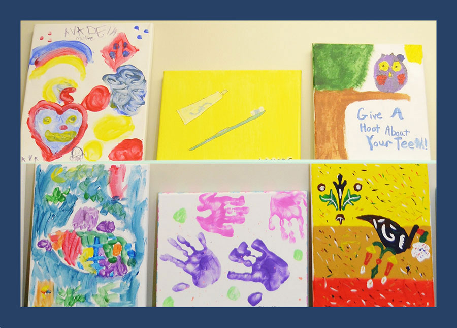 The image displays a collection of child-made artwork with various themes, displayed on a wall under clear lighting conditions.